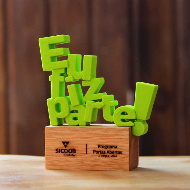Troféu impresso em 3D com letras em relevo sobre base de madeira
